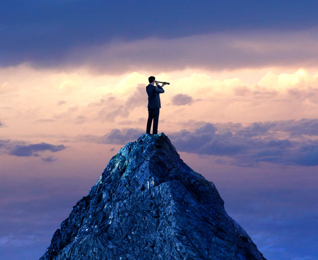 man with telescope on rock